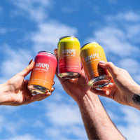 Four cans of SUMMi soda held up against a blue sky