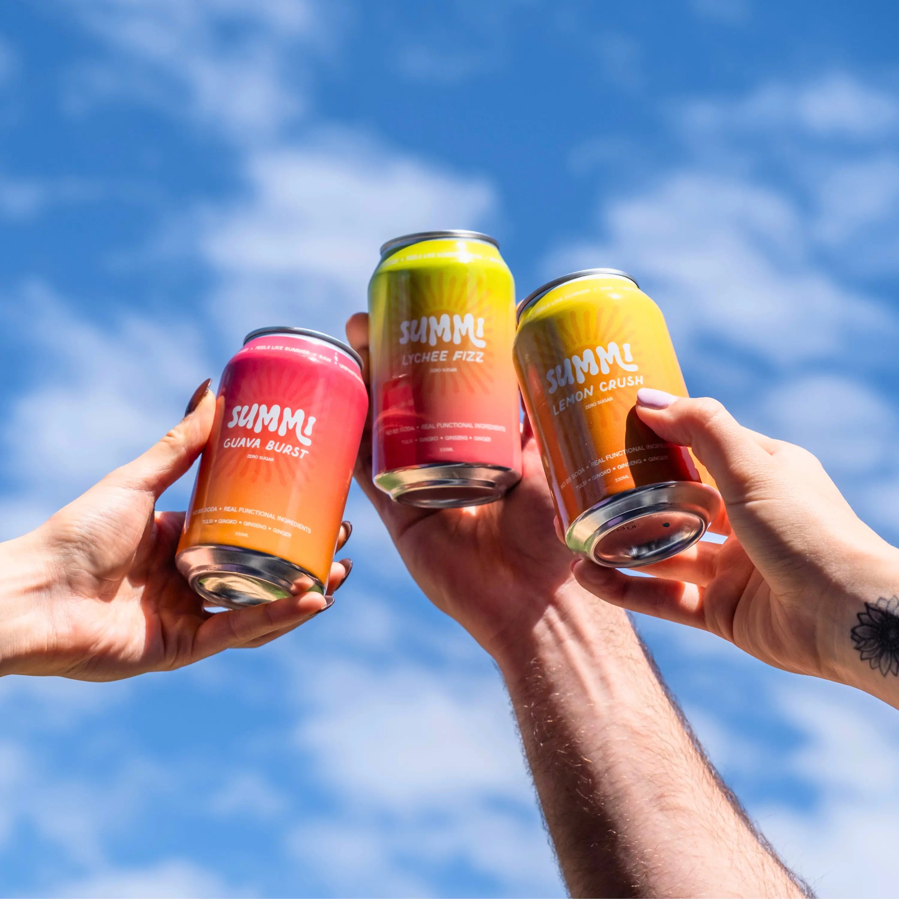 Four cans of SUMMi soda held up against a blue sky